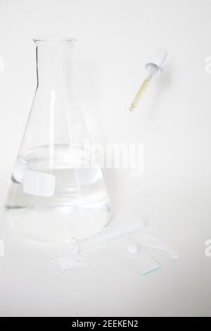 Laboratoire cosmétique ou chimique abstrait. Préparation d'un produit cosmétique. Flacons de produits chimiques transparents sur fond blanc. Tir vertical Banque D'Images