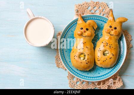 Viandes avec oignons verts et œuf, sous forme de lapin sur fond bleu clair avec lait, espace libre. Délicieuse pâtisserie maison de Pâques Banque D'Images