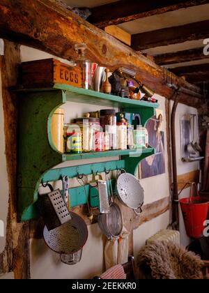 Plusieurs passoires de cuisine et des outils de cuisine partagent un ensemble d'étagères vert vintage contenant des ingrédients dans une maison de campagne à poutres apparentes. Sussex, Royaume-Uni Banque D'Images