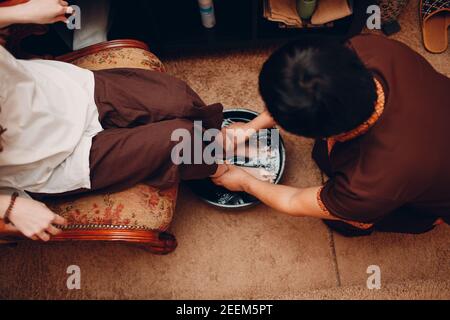 Homme thaïlandais se lavant les jambes et faisant un massage thaï classique procédure à la jeune femme au salon de beauté spa Banque D'Images