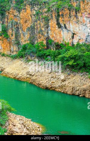 Lac à l'eau verte naturelle entouré par un mur de roches sédimentaires et sur la rive du lac, et la végétation verte. Photo au lac de Furnas, ca Banque D'Images