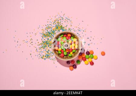 Plat de cuisson à gâteau de Pâques avec bonbons multicolores et garniture de confiserie parsemée sur fond rose. Concept d'arrière-plan festif. Faux Banque D'Images