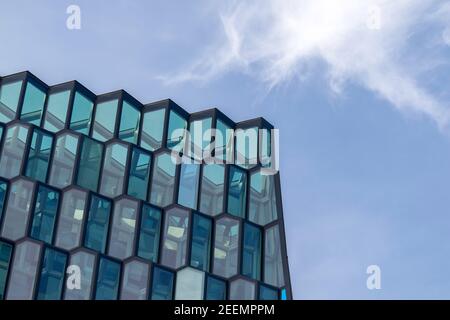 Vue de jour sur les fenêtres angulaires de la salle de concert de Reykjavik, Harpa, vue d'en dessous contre un ciel bleu avec des nuages sombres, avec un espace de copie Banque D'Images