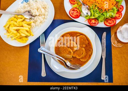 Cuisine traditionnelle de l'Alentejo - langue de vache dans une sauce servie avec salade, riz et frites, Portugal, Europe Banque D'Images