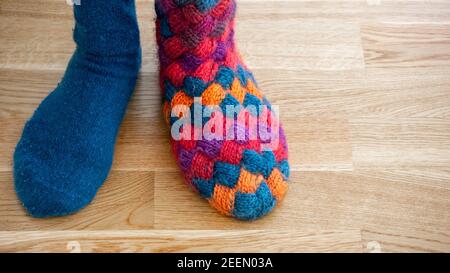 Une personne portant différentes chaussettes tricotées colorées faites main chaud, debout sur le sol. Concept de protestation individualité. Gros plan. Banque D'Images