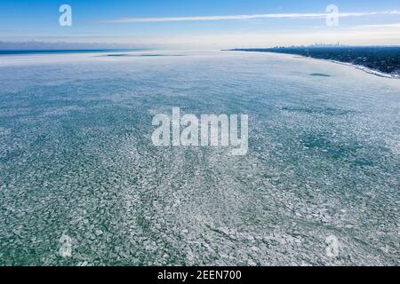 Vue aérienne d'un lac Michigan glacé avec la ligne d'horizon de Chicago vue au loin après une période de froid intense. Banque D'Images