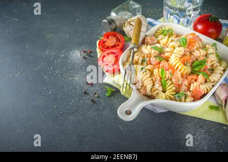 Alimentation de printemps pâtes végétaliennes saines. Pâtes italiennes fusilli avec tomates, légumes verts, herbes fraîches, fromage à la crème ou feta, sur fond de table sombre co Banque D'Images