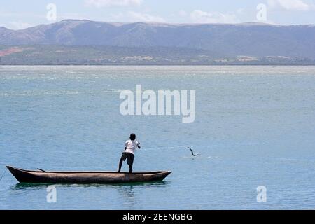 Un garçon malgache attrape une anguille d'un canot de dugout en bois, pirogue, Madagascar Banque D'Images