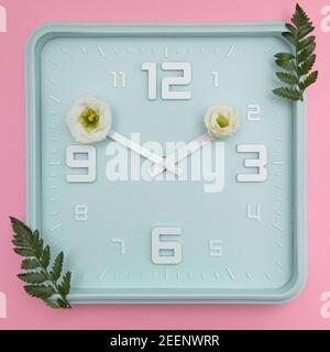 Horloge bleue avec fleurs sur les têtes, concept de l'heure du printemps. Le pastel colres un bel arrière-plan Banque D'Images