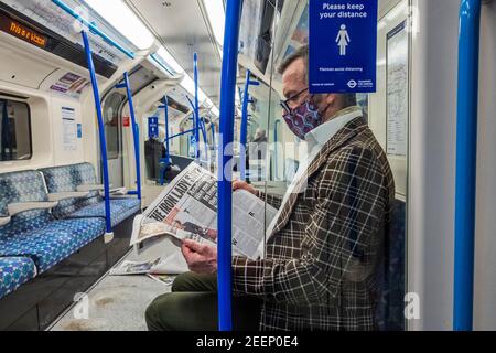 Londres, Royaume-Uni. 16 février 2021. Un homme dans une combinaison de masques de veste audacieux a lu ce que la dame de fer pourrait faire de tout - le métro est calme juste après l'heure de pointe pendant le nouveau lockdown national, rester à la maison, instructions. La plupart des voyageurs portent des masques car ils sont déjà obligatoires. Crédit : Guy Bell/Alay Live News Banque D'Images