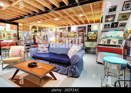 Une salle d'arcade sous-sol avec divers flippers rétro et jeux d'arcade classiques, vieux panneaux de compagnie d'acier et d'étain, et beaucoup de sièges. Banque D'Images