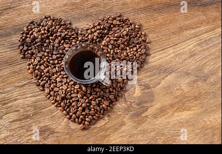 Tasse de café sur la forme du coeur fait de pile de grains de café sur texture en bois avec fond pour la Saint Valentin. Symbole de l'amour au café, Selectiv Banque D'Images