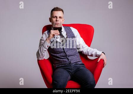 un jeune homme d'une manière officiellement professionnelle avec un verre de vin rouge Banque D'Images