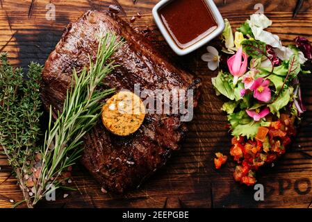 Steak grillé sur un plat de service en ardoise avec légumes herbes et épices Banque D'Images