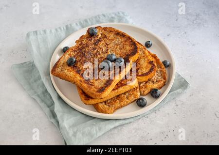 Vue de dessus de trois tranches de pain grillé avec bleuets sur une assiette sur fond gris, style minimaliste avec espace de copie Banque D'Images