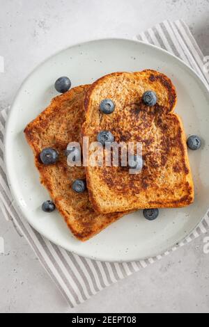 Gros plan à partir du dessus de deux tranches de pain grillé avec bleuets sur une assiette sur fond gris, style frais et propre, plat Banque D'Images