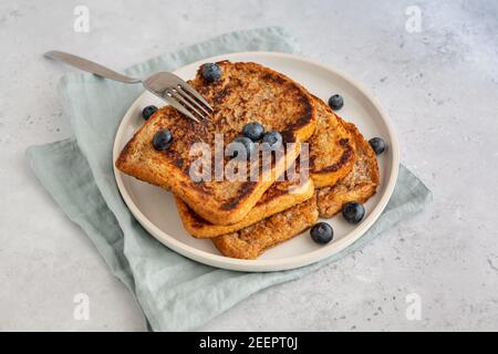 Vue de dessus de trois tranches de pain grillé et d'une fourchette avec des bleuets sur une assiette sur fond gris, style minimaliste avec espace de copie Banque D'Images