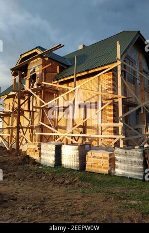Isolation de la maison avec des briques de façade, construction d'une nouvelle maison et échafaudage près des murs.New Banque D'Images