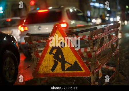 La route fonctionne devant le panneau à la nuit d'hiver rue près de la fosse - gros plan avec mise au point sélective Banque D'Images