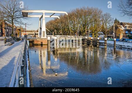 Delft, pays-Bas, 13 février 2021 : pont-bascule en acier blanc qui se reflète dans les flocons et la glace brisée du canal Rijn-Schie par une journée ensoleillée en hiver Banque D'Images