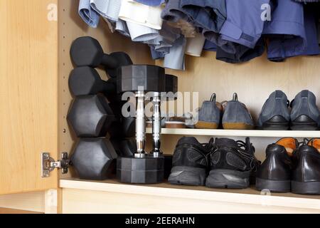 Remise en forme sociale : poids ou haltères et chaussures de course à pied au bas d'une garde-robe Banque D'Images