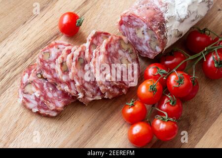 Tranché salami séché à l'air avec romarin et tomates cerises - bois arrière-plan Banque D'Images