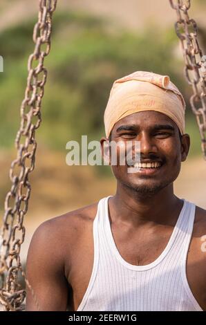 Ayodhya, Karnataka, Inde - 9 novembre 2013 : portrait d'un jeune fermier souriant, a du turban et un sous-maillot blanc. Se tient au niveau des chaînes de la balance. Banque D'Images