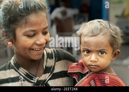 Jeune femme tenant l'enfant pleurant avec le nez qui coule et vivant dans les rues à Udaipur, Rajasthan, Inde. Banque D'Images