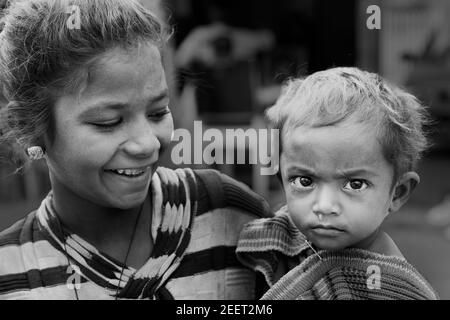 Jeune femme tenant l'enfant pleurant avec le nez qui coule et vivant dans les rues à Udaipur, Rajasthan, Inde. Banque D'Images