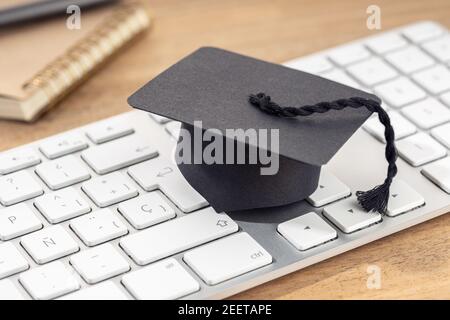 Concept d'apprentissage en ligne ou d'étude à domicile. Capuchon de graduation sur clavier d'ordinateur sur bureau en bois Banque D'Images