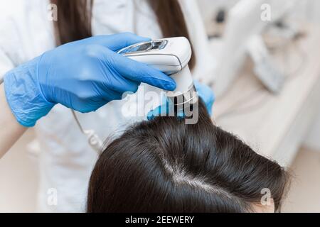 Trichocopie de la tête d'une femme avec un trichoscope gros plan. Banque D'Images