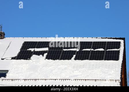 Panneau photovoltaïque partiellement couvert de neige en hiver dans un maison privée Banque D'Images