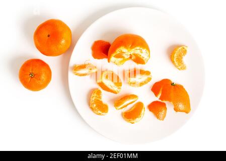 Peeling Tangerines ou Clementines avec un peu de vol stationnaire dans l'air, isolé sur fond blanc Banque D'Images