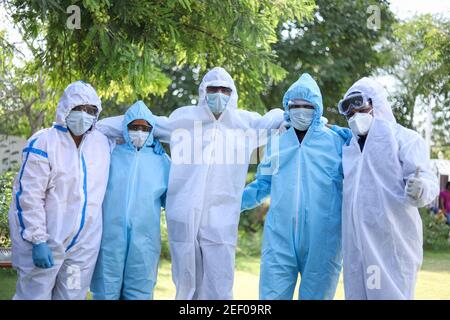 Groupe optimiste de travailleurs médicaux portant des vêtements de protection et posant pour une photo Banque D'Images