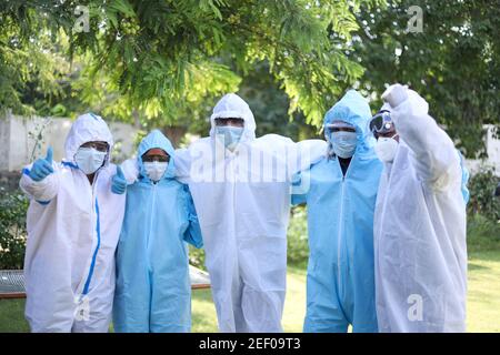 Groupe optimiste de travailleurs médicaux portant des vêtements de protection et posant pour une photo Banque D'Images