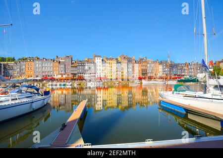 Une rangée de maisons, d'entreprises et de cafés-terrasses se reflètent au large de l'eau dans le vieux port de Honfleur France sur la côte normande Banque D'Images