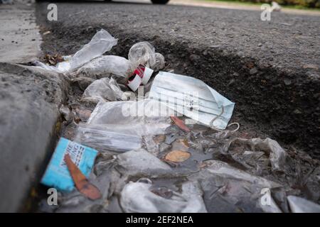 Un masque de protection jeté allongé sur le trottoir d'une route avec d'autres déchets en plastique. Cebu City, Philippines Banque D'Images