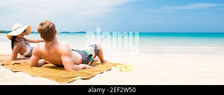 Couple allongé sur une plage de sable blanc relaxant et prenant un bain de soleil en été - bannière web panoramique avec espace copie Banque D'Images