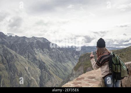 COLCA CANYON, PÉROU - 20 JANVIER 2018 : une touriste prend une photo avec son téléphone mobile dans un magnifique point de vue sur Colca Canyon, Arequipa, Pérou Banque D'Images