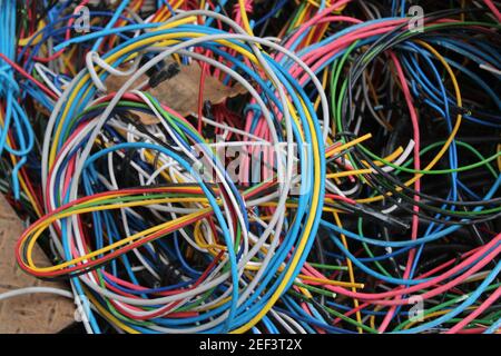 Fils et câbles multicolores enroulés dans un tas derrière un atelier d'électricien local Banque D'Images