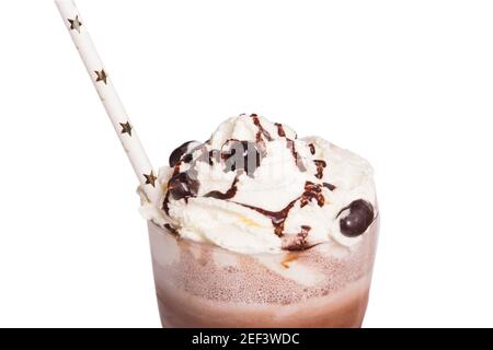 gros plan de verre avec milk-shake au chocolat enrobé de crème au caramel et grains de chocolat avec paille décorée avec des étoiles étincelantes arrière-plan blanc Banque D'Images
