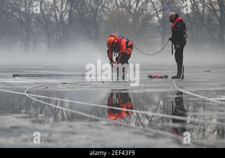 16 février 2021, Hessen, Francfort-sur-le-main : un pompier de l'équipe de secours en eau du service des incendies de Francfort-sur-le-main utilise une tronçonneuse pour percer un trou dans l'étang gelé d'Ostpark au début d'un exercice de plongée. La glace sur les lacs et les étangs gelés est tentante - mais malgré sa stabilité apparente, elle peut être mortelle. Pour être en mesure d'aider dans de tels cas, les plongeurs des pompiers doivent également s'entraîner dans les opérations de secours. Cet hiver, les conditions sont bonnes pour cela. (À dpa 'sauvetage de glace comme un cas de formation - une première pour les jeunes pompiers') photo: Arne Dedert/dpa Banque D'Images