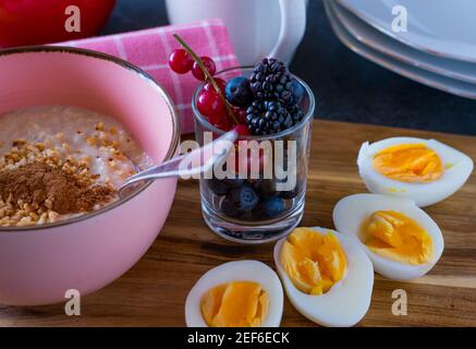 petit-déjeuner végétarien avec un bol de porridge, des baies fraîches et des œufs durs Banque D'Images