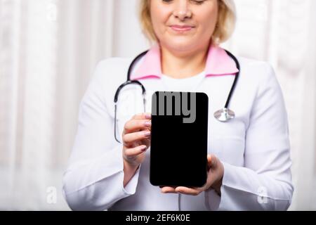 Prise de vue rognée d'une femme médecin à l'aide d'une tablette numérique, montrant un modèle d'écran vide à l'appareil photo. Mise au point sélective sur la tablette numérique. Médical en ligne Banque D'Images