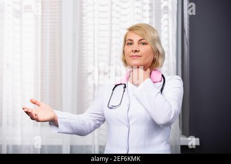 Une femme âgée a froissé son visage et tient sa main près de la gorge, mal de gorge problèmes de santé. Affiche la deuxième main ouverte à distance à vide Banque D'Images