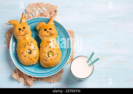 Viandes avec oignons verts et œuf, sous forme de lapin sur fond bleu clair avec lait, espace libre. Délicieuse pâtisserie maison de Pâques Banque D'Images