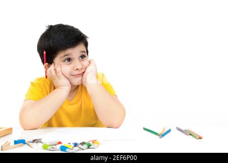 Mignon petit garçon pensant à ce qu'il faut dessiner et peindre - apprentissage, éducation et imagination concepts Banque D'Images