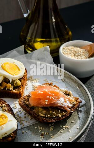 Pains grillés avec œufs pochés, avocat et saumon. Sandwichs au guacamole. Petit déjeuner sain. Huile d'olive. Graines de sésame. Alimentation saine végétarienne. Régime alimentaire. Mise au point sélective snack, gros plan Banque D'Images