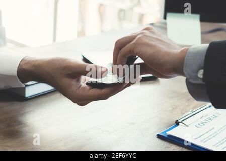 Homme d'affaires donnant de l'argent à son partenaire tout en faisant le contrat - les concepts de corruption Banque D'Images
