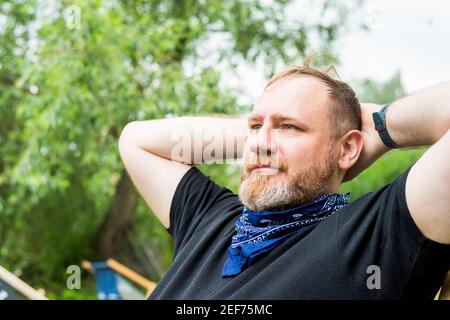 un homme adulte se détend en plein air dans un jardin de plage de la ville, tenant les mains derrière la tête. activités solo en plein air Banque D'Images